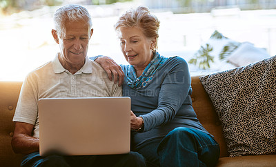 Buy stock photo Shot of a happy senior couple using a laptop together on the sofa at home