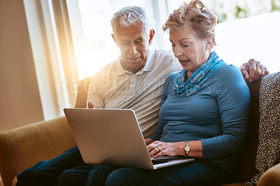 Buy stock photo Shot of a senior couple using a laptop together on the sofa at home