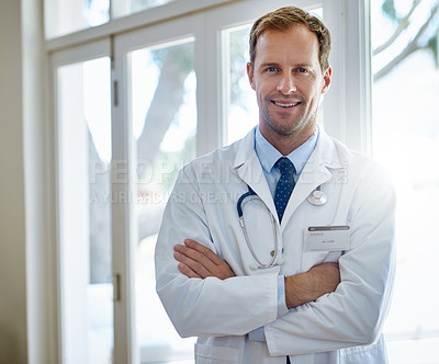 Buy stock photo Portrait of a smiling male doctor standing with his arms crossed in a hospital