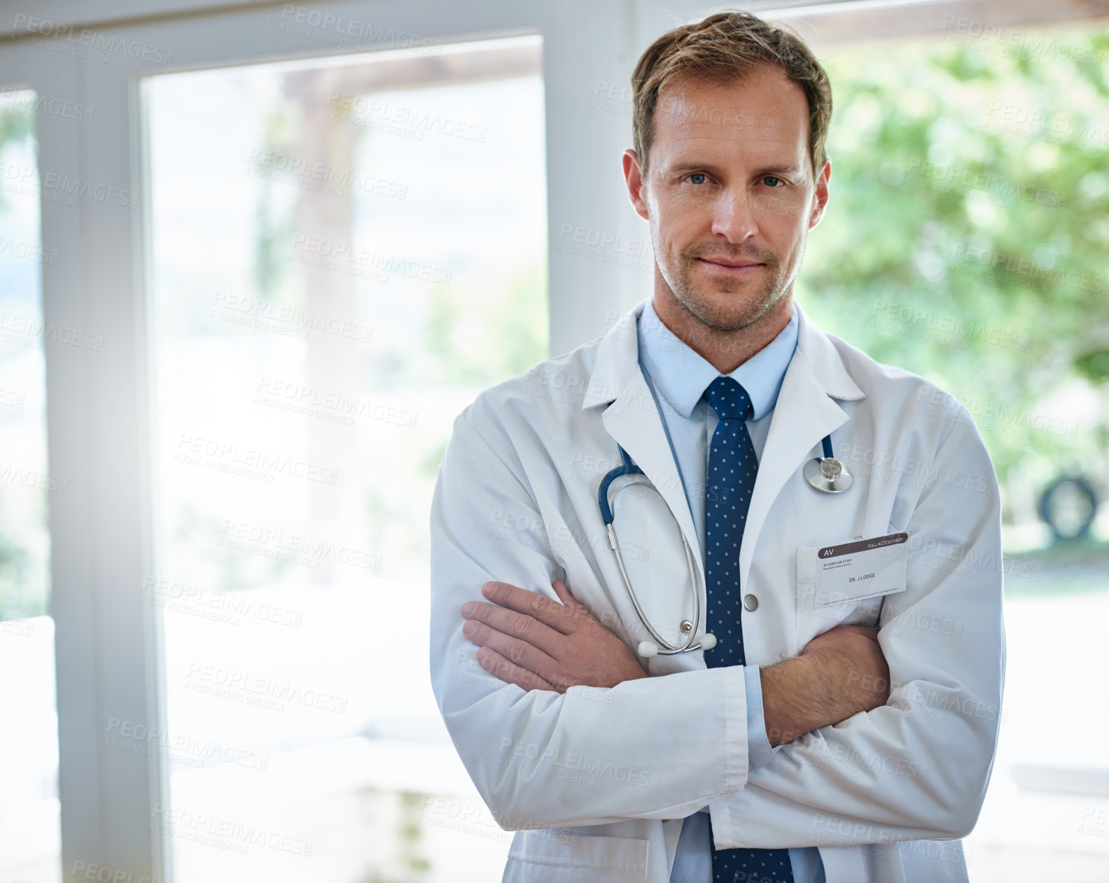 Buy stock photo Portrait of a male doctor standing with his arms crossed in a hospital