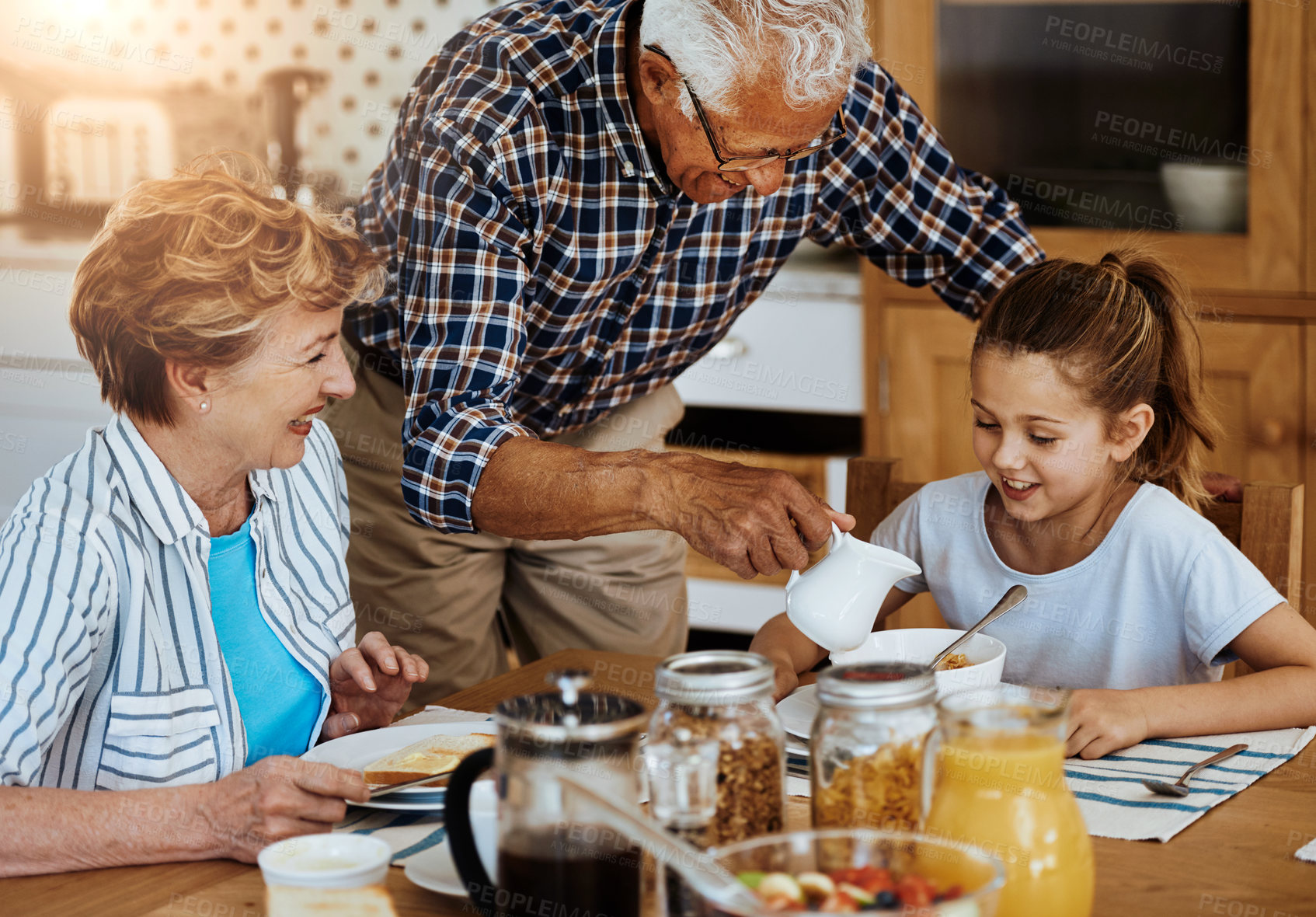 Buy stock photo Cropped shot of a little girl having breakfast with her grandparents at home
