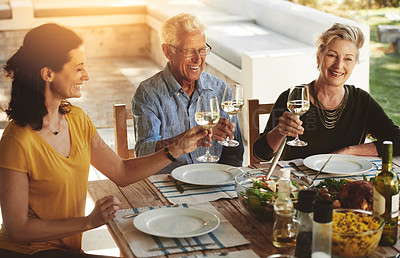 Buy stock photo Shot of a happy family enjoying lunch together around a table outside