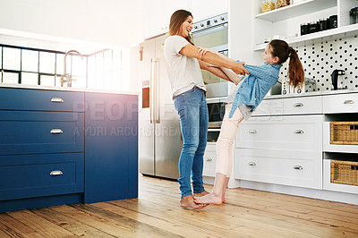 Buy stock photo Shot of a happy mother and daughter playfully dancing together at home