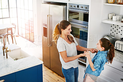 Buy stock photo Shot of a happy mother and daughter playfully dancing together at home