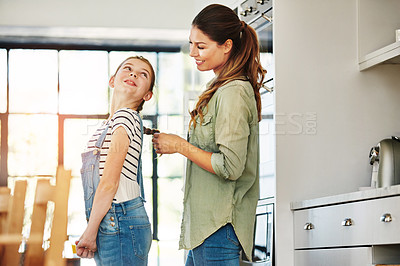 Buy stock photo Shot of a happy mother braiding her daughter’s hair at home