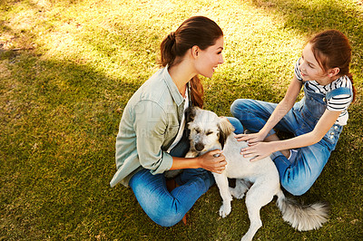 Buy stock photo Shot of a mother and her daughter playing with their dog at the park