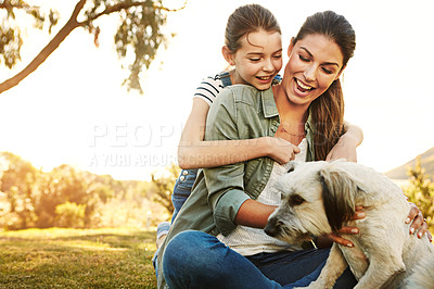 Buy stock photo Shot of a mother and her daughter playing with their dog at the park