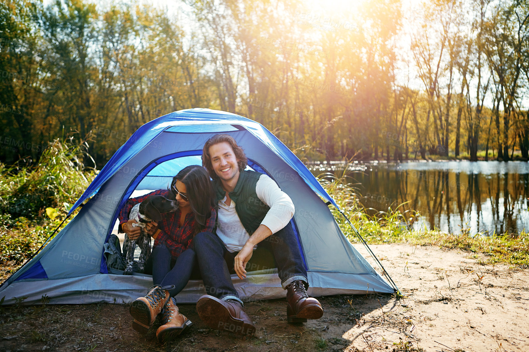 Buy stock photo Couple, dog and camping by tent in nature for adventure, freedom and vacation or peace. People, puppy and relax in woods or forest by lake for summer holiday, memory and outdoor experience at morning