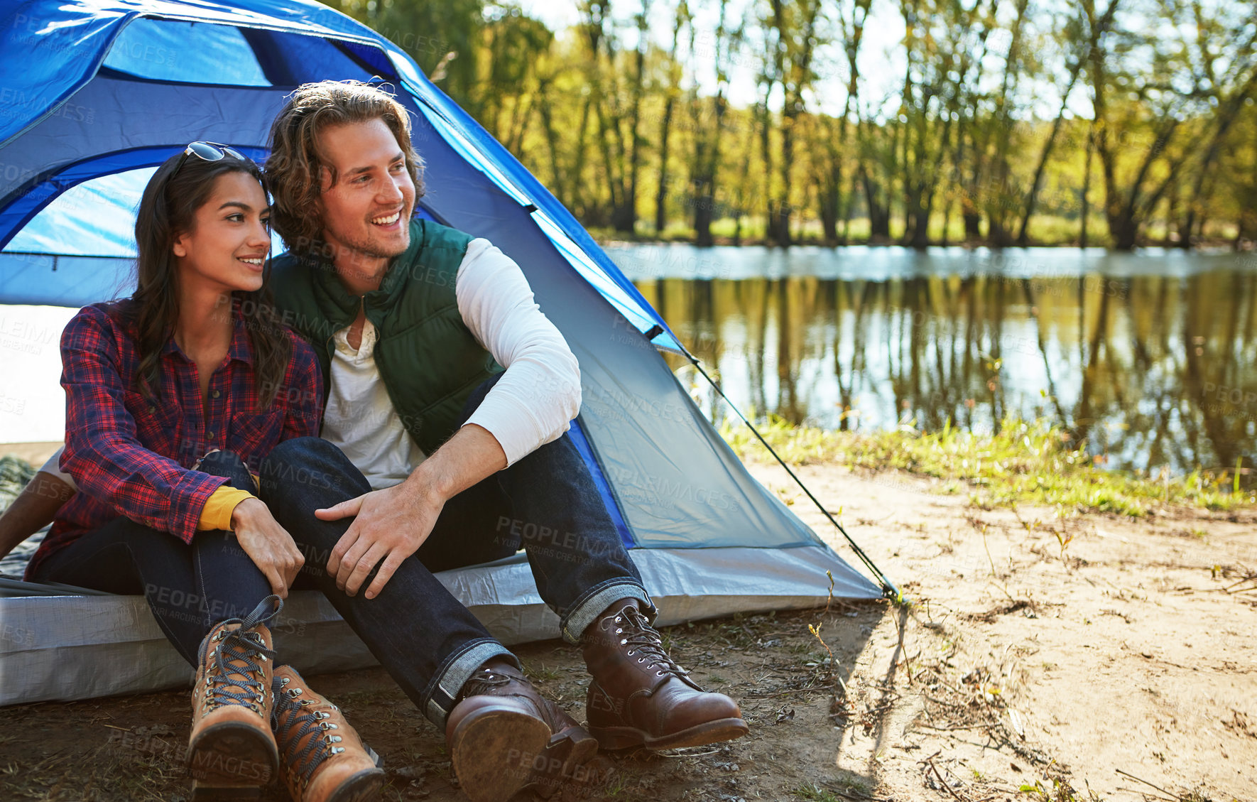 Buy stock photo Happy couple, relax and tent by river for camping, bonding together outdoor and connection with nature. Dating, love and people by lake with campsite, travel activity and adventure for weekend break.