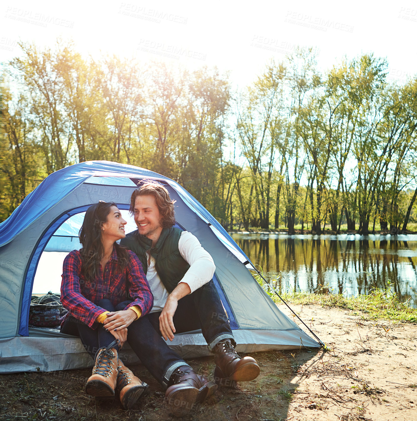 Buy stock photo Camping, holiday and couple in tent with love and happiness together on adventure in woods at lake. People, embrace or relax outdoor in nature with funny chat on vacation or travel to river in forest