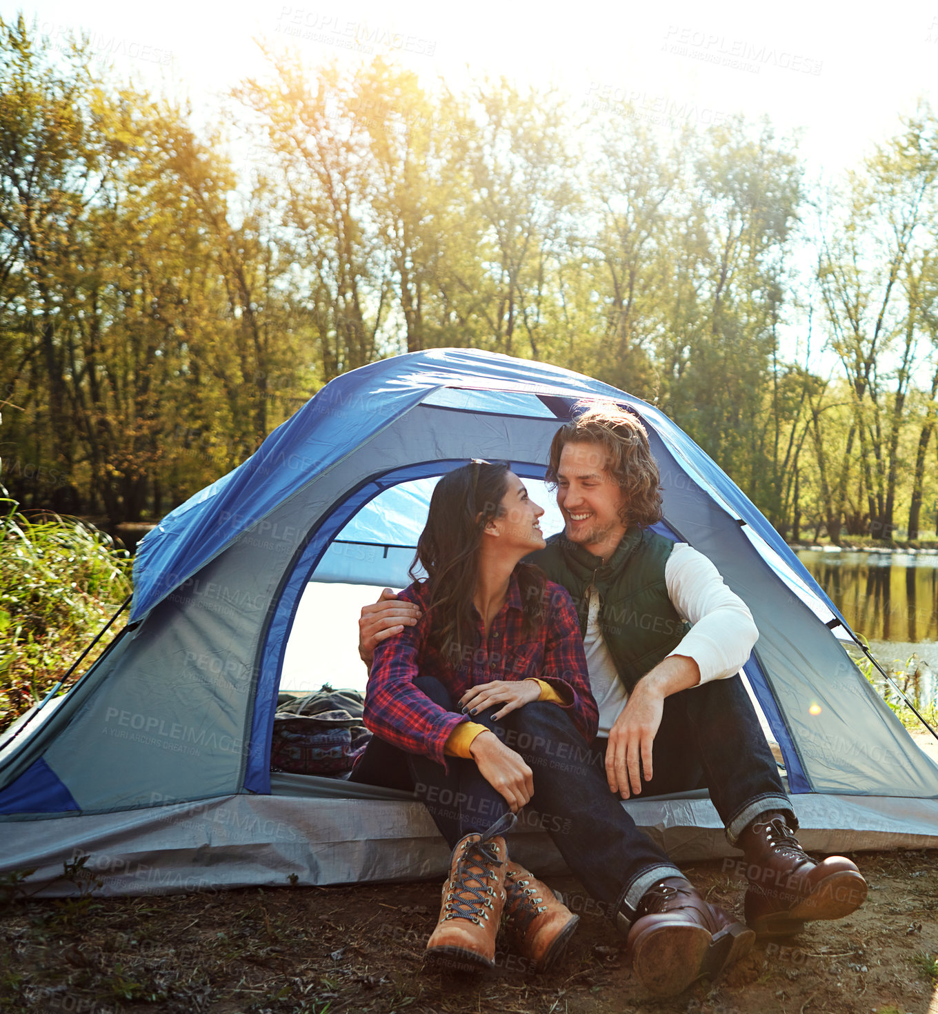 Buy stock photo Couple, hug and relax in tent or camping with love and happiness together on adventure in woods. People, embrace or relax outdoor in nature with funny chat on vacation or travel to river in forest