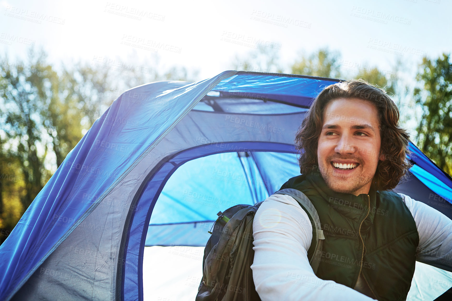 Buy stock photo Cropped shot of a handsome young man sitting at his campsite