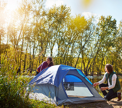 Buy stock photo Shot of an adventurous setting up their tent by the lake