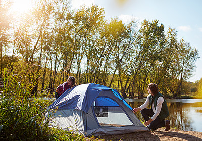 Buy stock photo Shot of an adventurous setting up their tent by the lake