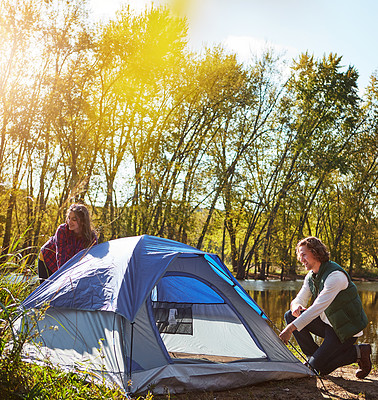 Buy stock photo Shot of an adventurous setting up their tent by the lake