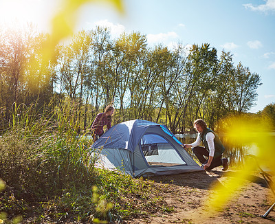 Buy stock photo Shot of an adventurous setting up their tent by the lake