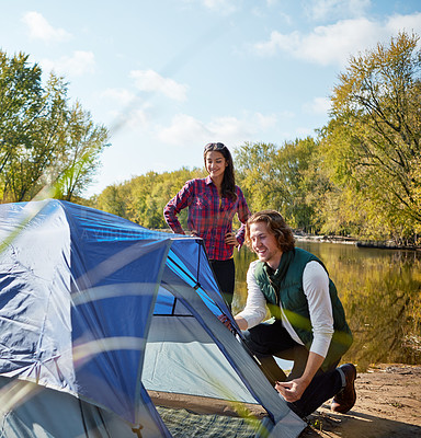 Buy stock photo Shot of an adventurous setting up their tent by the lake