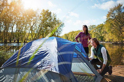 Buy stock photo Shot of an adventurous setting up their tent by the lake