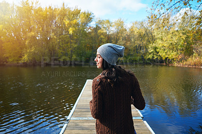 Buy stock photo Shot of a happy young woman standing on a pier next to a lake