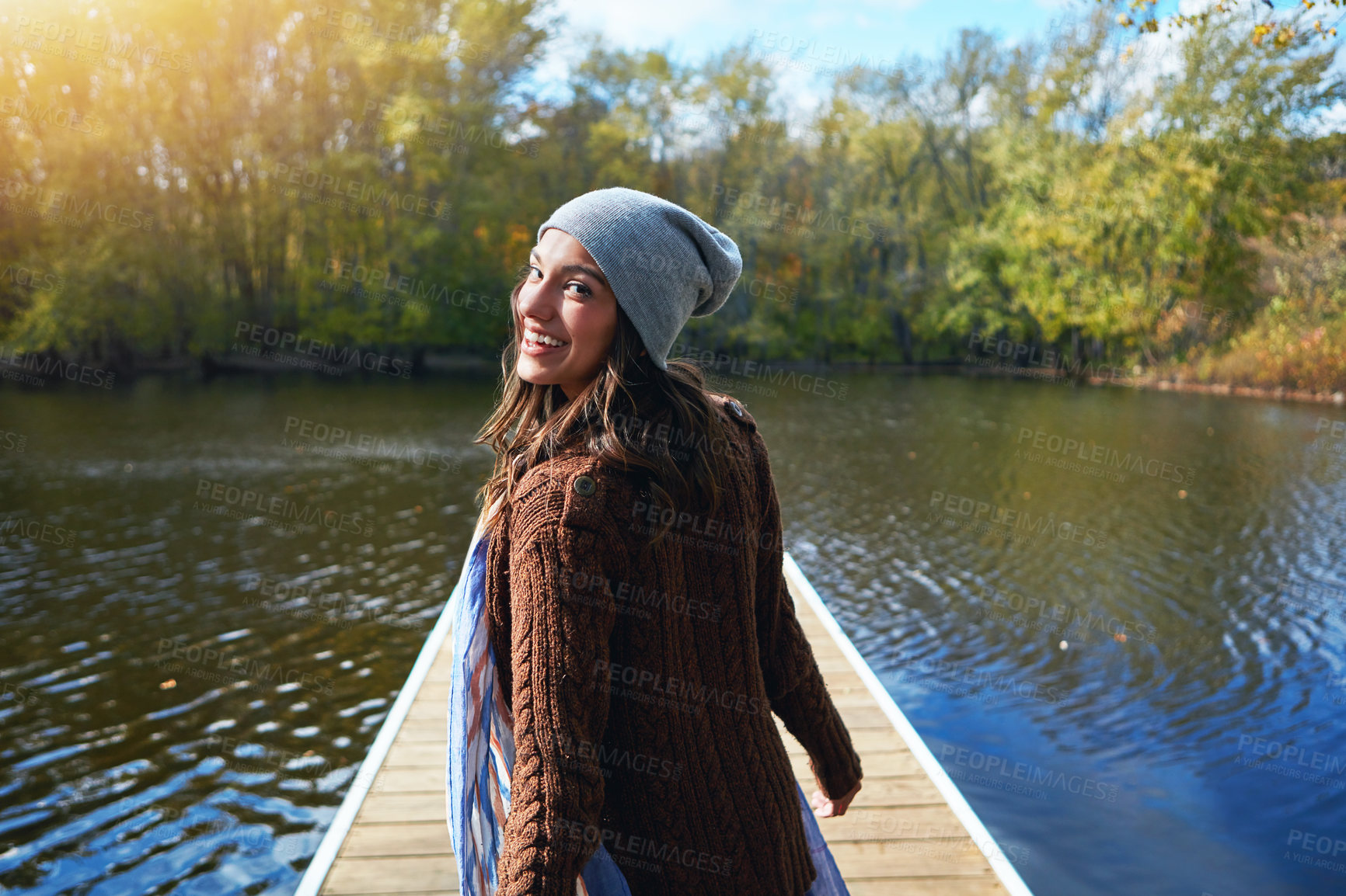 Buy stock photo Portrait of a happy young woman standing on a pier next to a lake