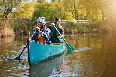 Buy stock photo Shot of a young couple going for a canoe ride on the lake