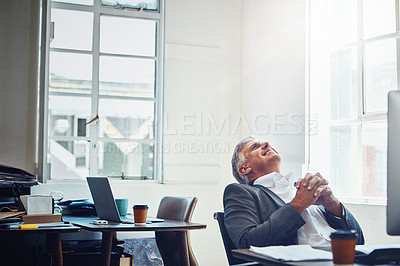 Buy stock photo Shot of a mature businessman taking a break at his office desk