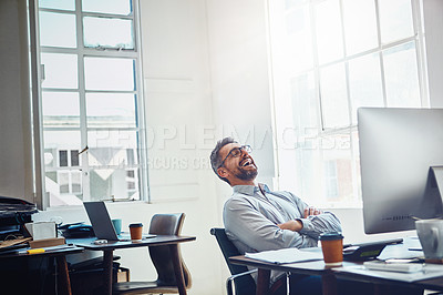 Buy stock photo Shot of a mature businessman laughing while working on a computer in an office