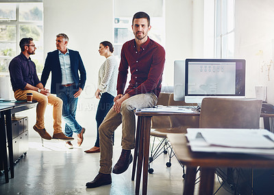 Buy stock photo Portrait of a young man with his colleagues having a discussion in the background