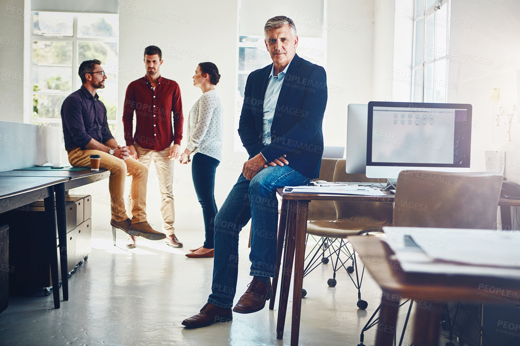 Buy stock photo Portrait of a mature man posing while his colleagues stand in the background