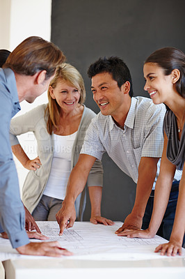 Buy stock photo Shot of a group of coworkers looking over a set of plans