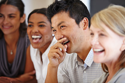 Buy stock photo Shot of an Asian man laughing at a table with his coworkers out of focus
