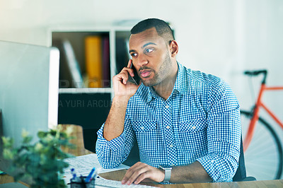 Buy stock photo Shot of a handsome young businessman making a phonecall while working in his office