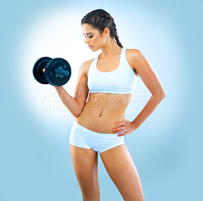 Buy stock photo Studio shot of an attractive young woman working out with a dumbbell against a blue background