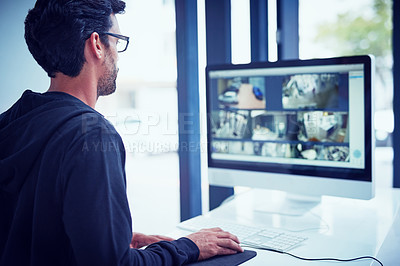 Buy stock photo Cropped shot of a young man watching security footage on his computer
