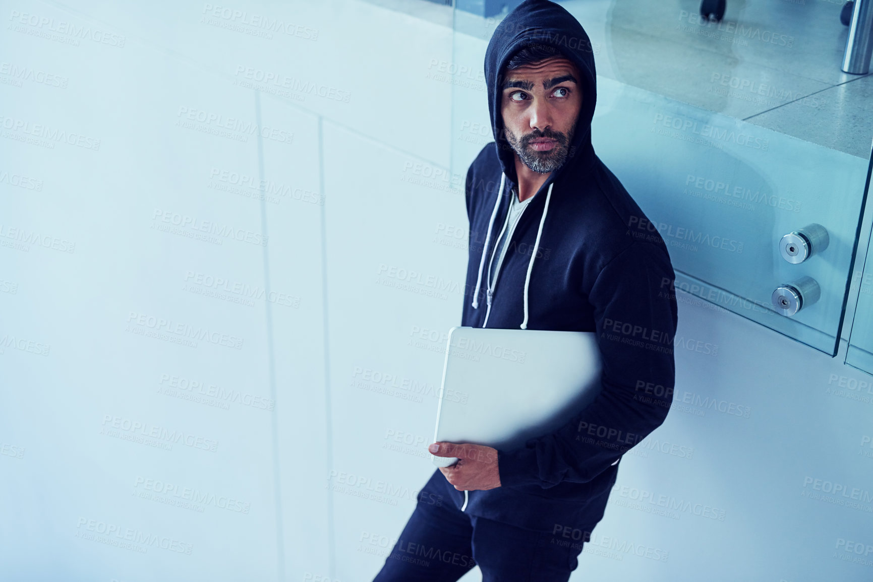 Buy stock photo Stealing, laptop and man in hoodie for crime, theft or taking digital information from office building. Male criminal, security or computer in hands of robber for danger, robbery or suspicious person