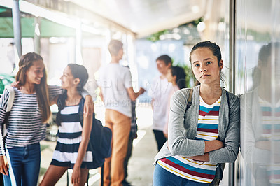 Buy stock photo Portrait of a lonely schoolgirl standing outside her classroom with classmates in the background