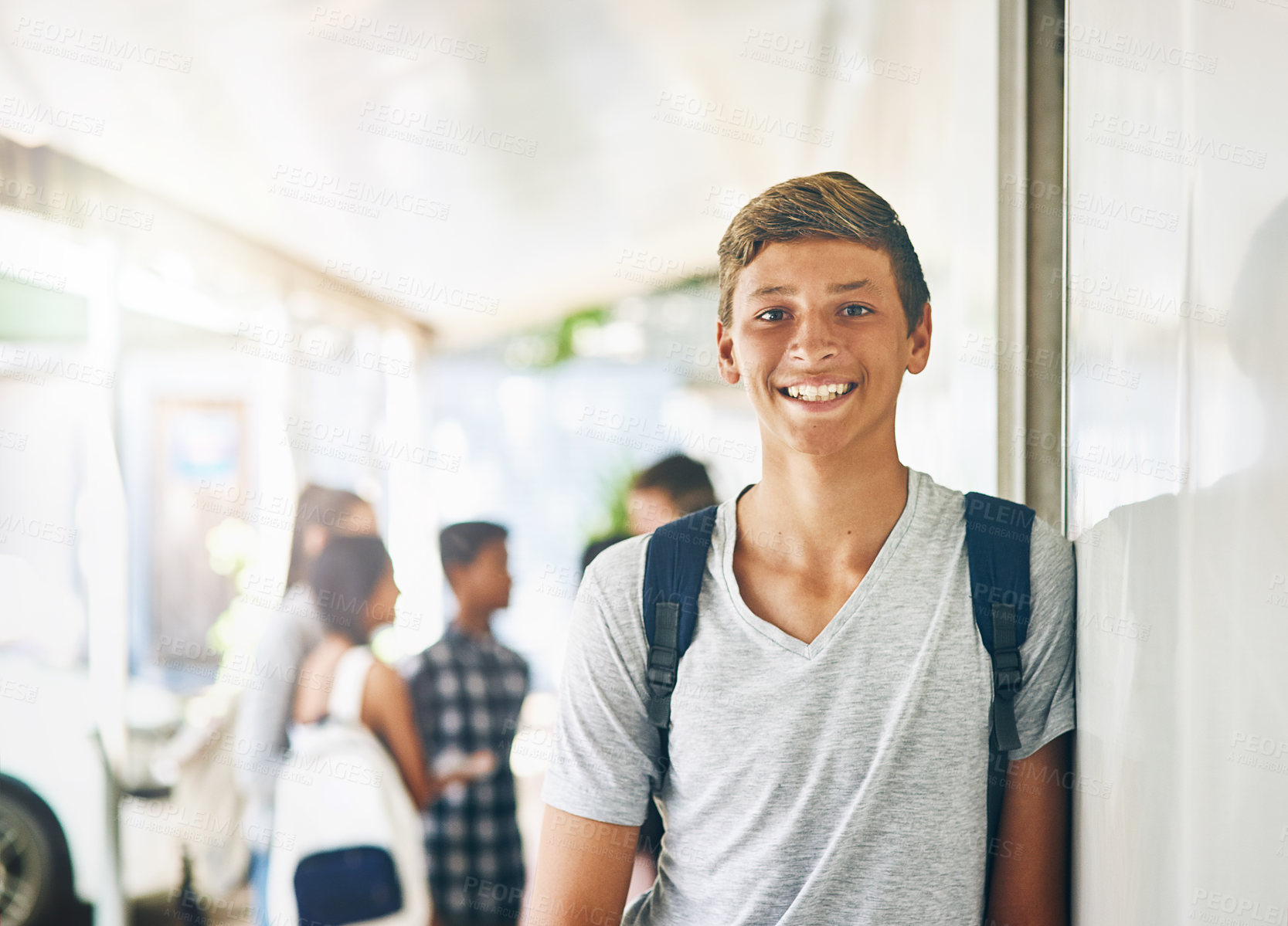 Buy stock photo Portrait of a happy schoolboy standing outside his classroom with classmates in the background