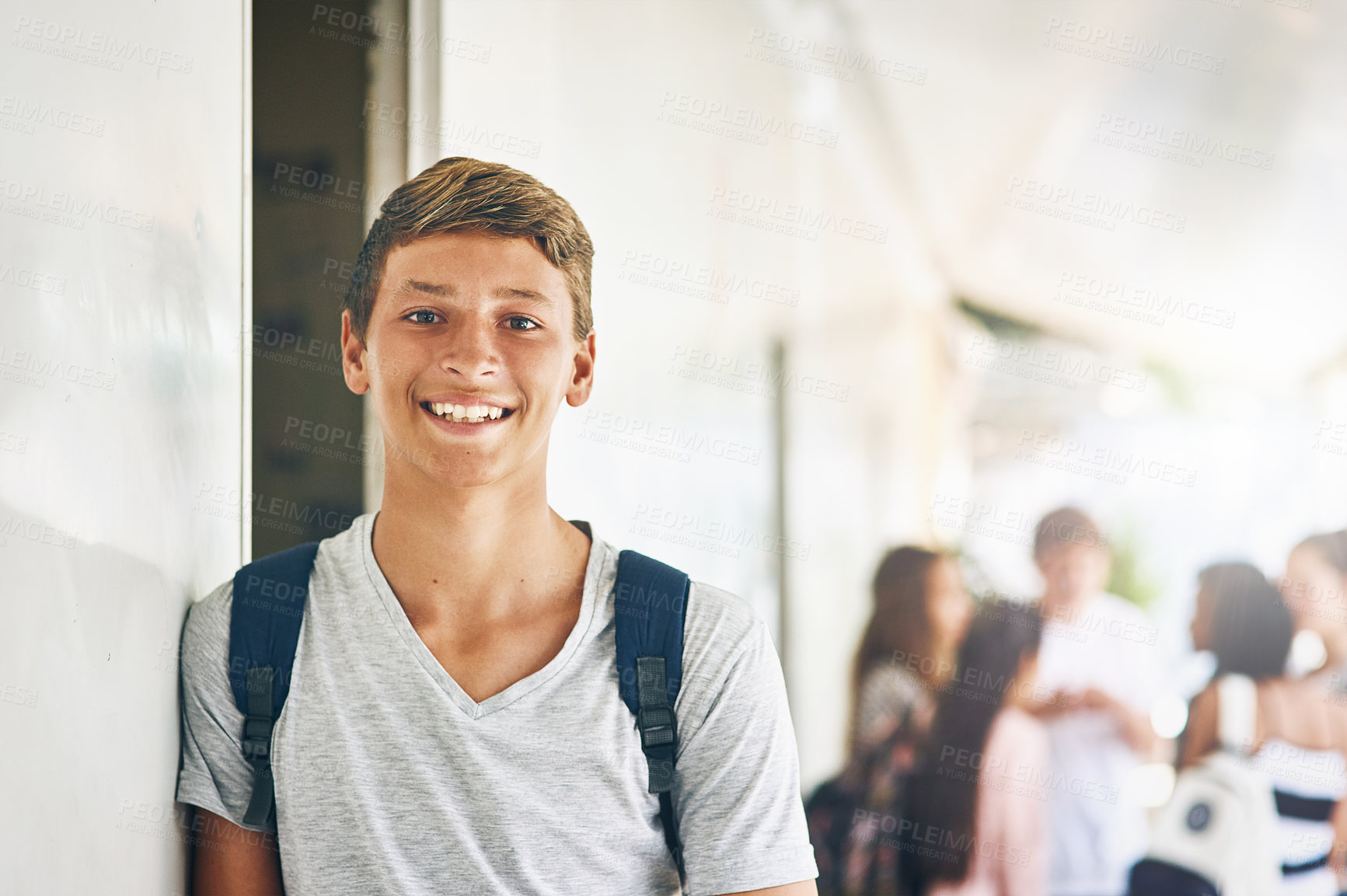 Buy stock photo Portrait of a happy schoolboy standing outside his classroom with classmates in the background