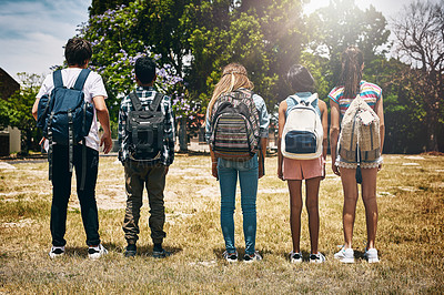 Buy stock photo Rearview shot of a group of unidentifiable schoolchildren standing in a line in a park