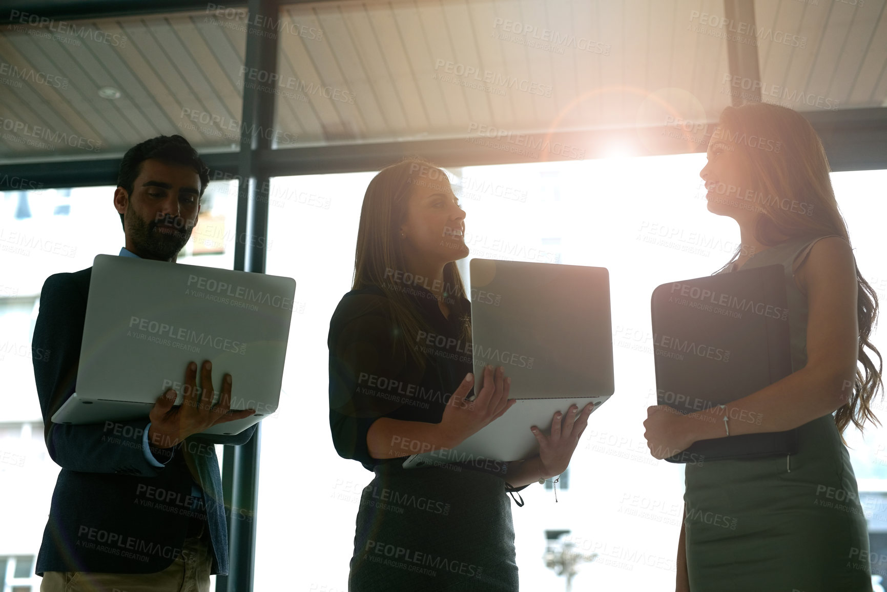 Buy stock photo Cropped shot of three coworkers meeting with their laptops in the lobby