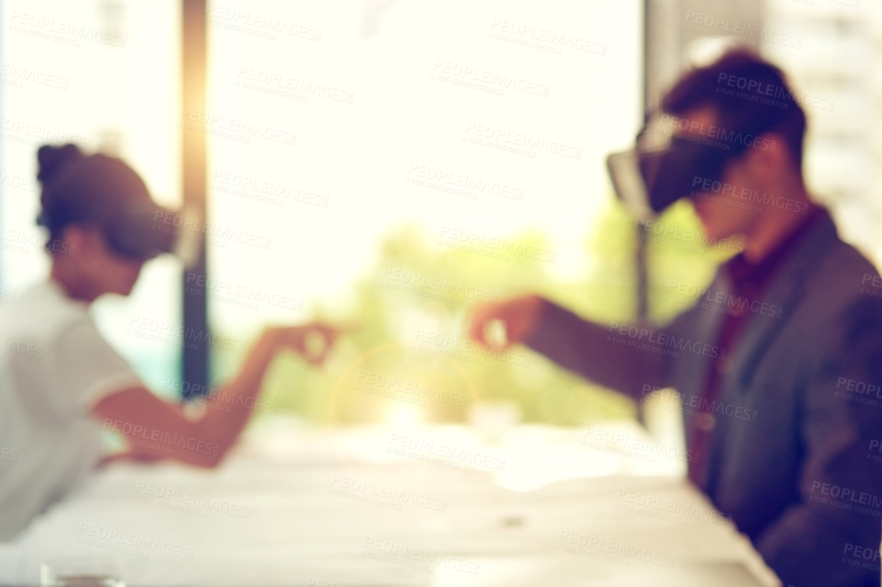 Buy stock photo Defocused shot of two businesspeople wearing VR headsets while working together in an office