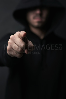 Buy stock photo Dark, criminal and man in studio, pointing and undercover for stalking, person and thief with crime. Black background, scam and hiding with hoodie, burglary and creepy in shadows, villain and fraud