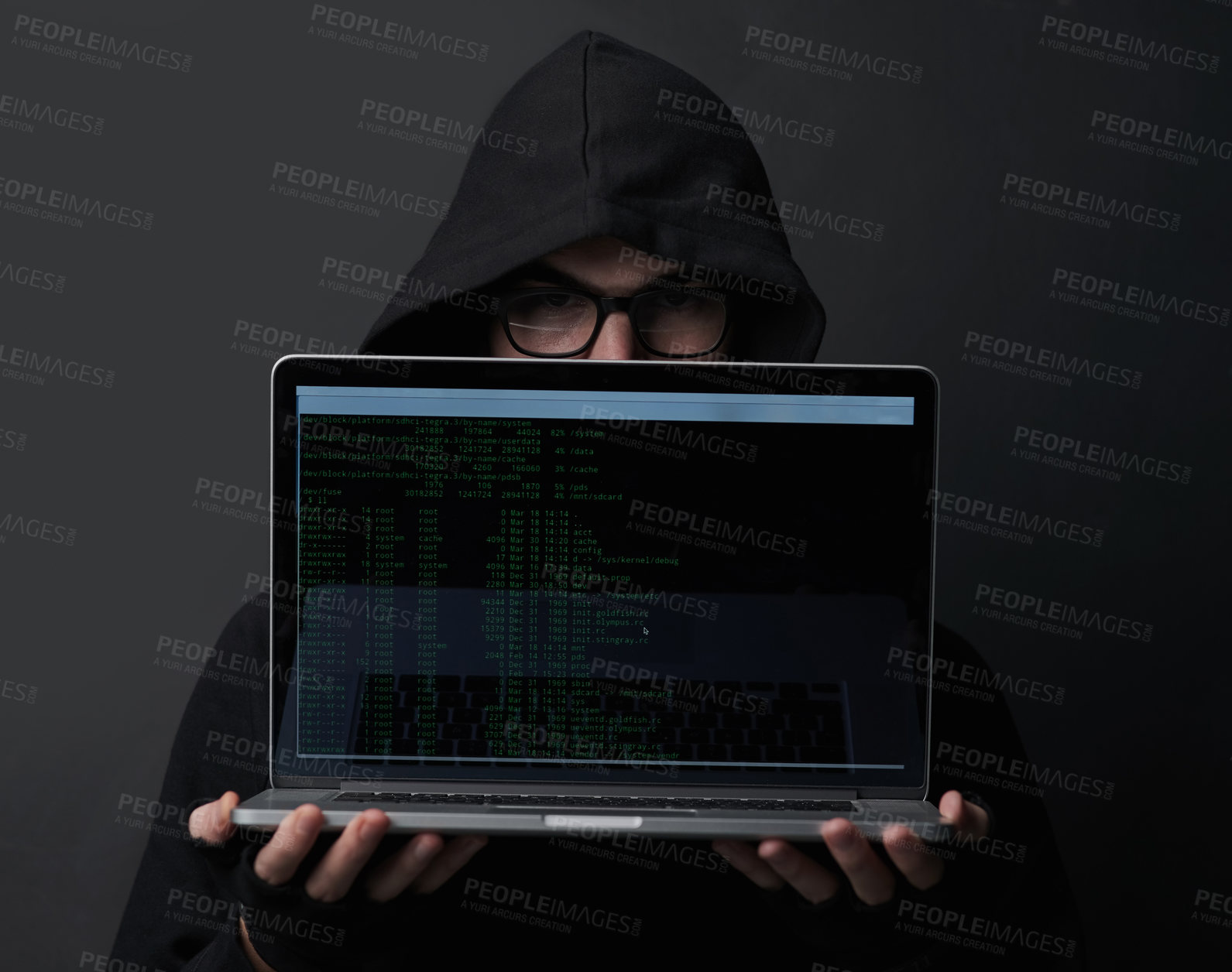 Buy stock photo Portrait of an unidentifiable computer hacker holding up a laptop against a dark background