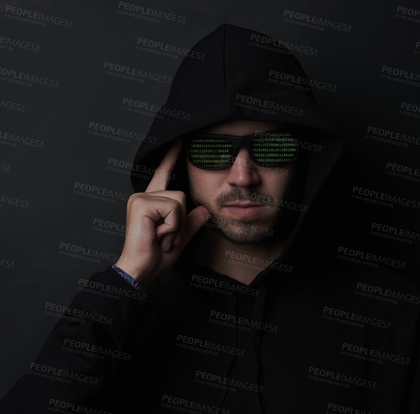 Buy stock photo Shot of an unidentifiable man wearing sunglasses and a hoodie while posing against a dark background