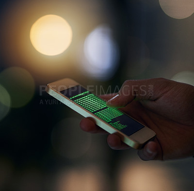 Buy stock photo Shot of an unidentifiable computer hacker using a smartphone to hack into a network