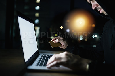 Buy stock photo Shot of a serious criminal using a laptop to hack into a credit account