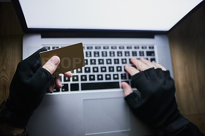 Buy stock photo Shot of an unidentifiable criminal using a laptop to hack into a credit account