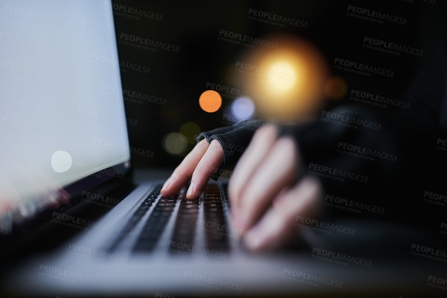 Buy stock photo Shot of an unrecognizable computer hacker using a laptop late at night