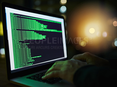Buy stock photo Shot of an unrecognizable computer hacker using a laptop late at night