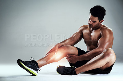 Buy stock photo Full length shot of a sporty young man nursing a calf injury against a grey background